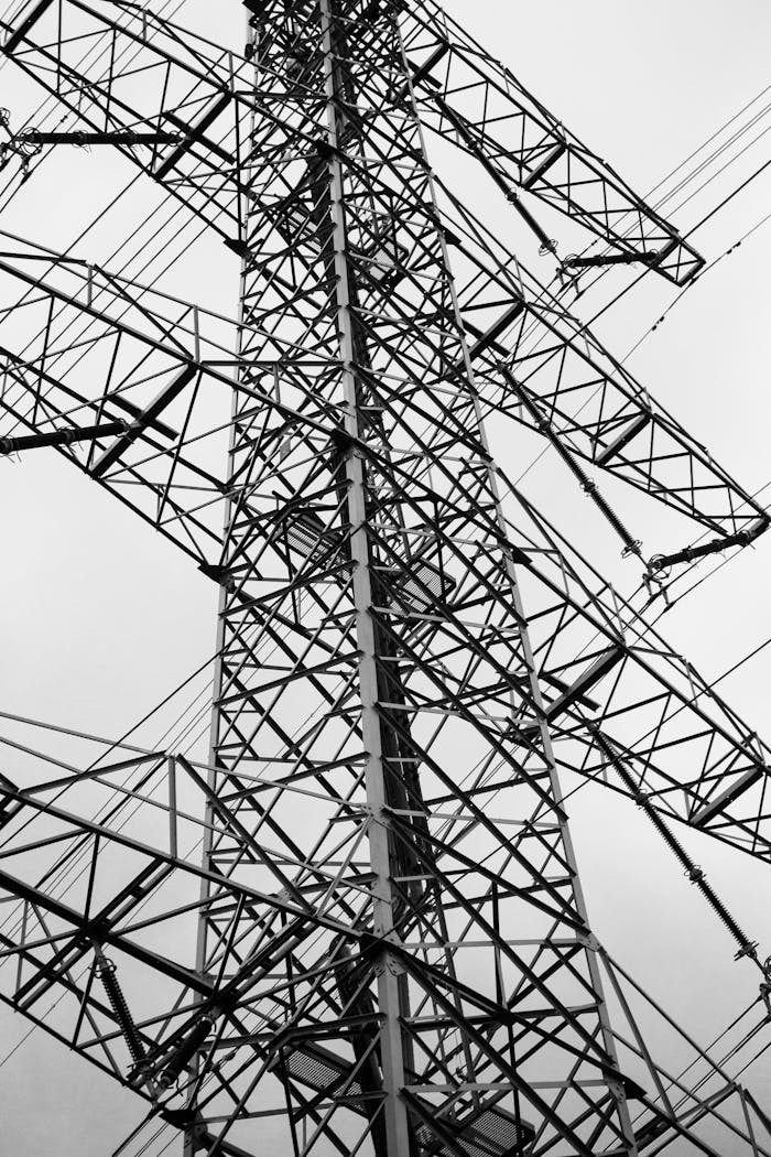 Close-up of a steel-framed high voltage tower captured against a cloudy sky.